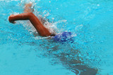 Fototapeta Łazienka - Young man swimmer with blue cap swims front crawl or forward crawl stroke in a swimming pool for competition or race