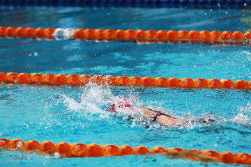 Asian girl with red cap swim free style or forward crawl in swimming pool for competition or race