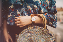 Street Style Fashion Details. Woman Wearing A Summer Shirt And A White And Brown Analog Wrist Watch, Holding A Round Straw Purse. Perfect Summer Fashion Accessories. Warm Vintage Grade