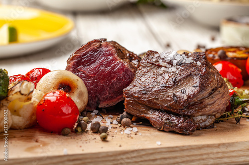 Fotografía Two juicy steaks with roast medium rare, with grilled vegetables on a wooden board