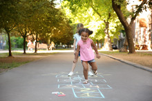 Little Children Playing Hopscotch Drawn With Colorful Chalk On Asphalt