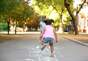 Sticker - Little children playing hopscotch drawn with colorful chalk on asphalt