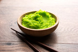 Fototapeta  - Green wasabi sauce or paste in bowl, with chopsticks or spoon over plain colourful background. selective focus
