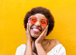 Fashion hippie african woman smiling and wearing sunglasses with yellow ochre wall in background - Black afro girl having fun - Youth lifestyle, trendy and happiness concept