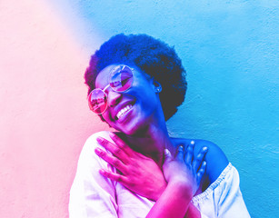 Millennial african woman smiling and wearing sunglasses - Black afro girl having fun in front of camera - Youth lifestyle concept - Radial blue and purple filter editing