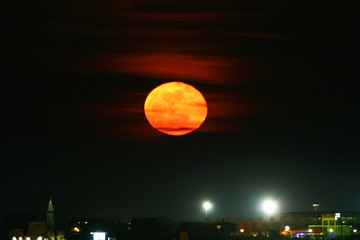 full moon above the city stadium and church at night.