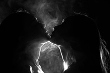 Silhouette Of Two Sexy Woman Kissing Holding In Darkness Through Light And Smoke