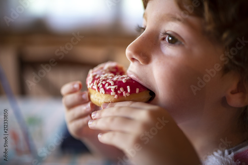 Fotomural Bambina che mangia un goloso dolce alla fragola, con granella di zucchero