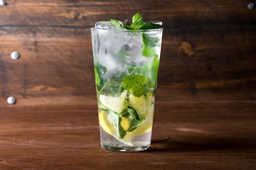 Classical mojito with lemon, soda, mint in glass on wooden background