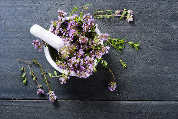 Wall Mural - thyme flowers in a mortar on dark wood table