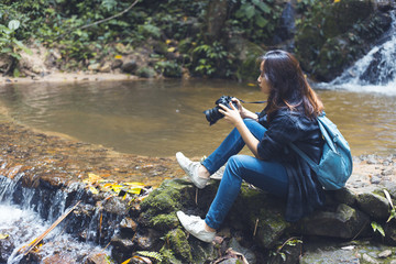 Wall Mural - Photography and traveling Girls carrying cameras are on the waterfront in the jungle.