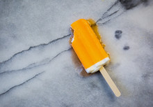 Melting Orange Creamsicle Popsicle With A Bite Out Of It.