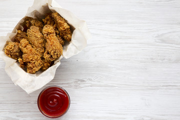 Wall Mural - Spicy fried chicken wings with sauce on a white wooden surface, top view. From above, flat, overhead. Copy space and text area.