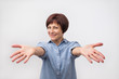 © Viktor Koldunov - Portrait of attractive mature woman raised up arms hands at you. She is dressed in blue shirt. Happy to welcome a friend or guest