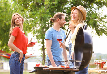 Canvas Print - Young people having barbecue with modern grill outdoors