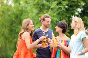 Canvas Print - Young people with bottles of beer and food outdoors. Summer barbecue