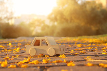 Old Wooden Toy Car On The Road Outdoors In The Park At Sunset. Nostalgia And Simplicity Concept.