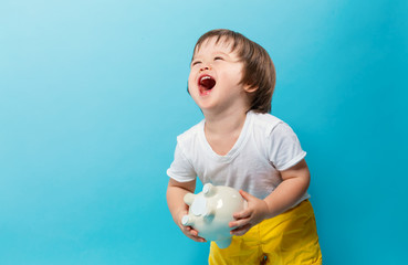 Wall Mural - Toddler boy with a piggy bank on a blue background