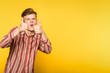 approving comic funny eccentric man showing thumbs up gesture. portrait of a young guy on yellow background. copyspace for advertisement.