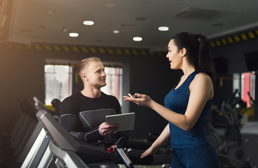 Fitness coach helps woman on elliptical trainer