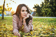© dobok - young woman lying down on the ground in a park in autumn