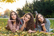 © dobok - three girlfriends lying on the grass in a park in autumn