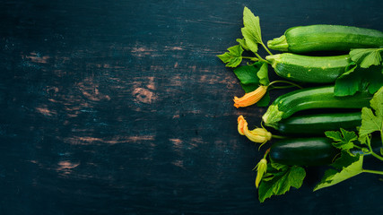 Fresh green zucchini on a black wooden table. Top view. Copy space.