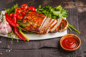 Wall Mural - Roasted pork with thyme, rosemary, garlic and tomato sauce on a white dish, dark background, copy space.