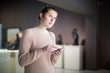 © JackF - woman using smartphone and standing in art museum