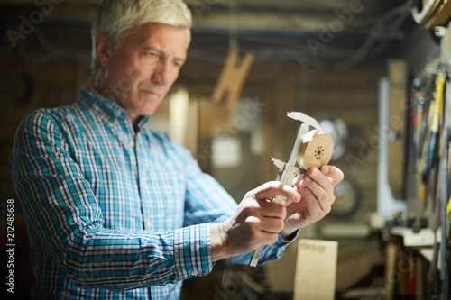 Fotografía Professional engineer measuring diameter of round wooden workpiece in his workro
