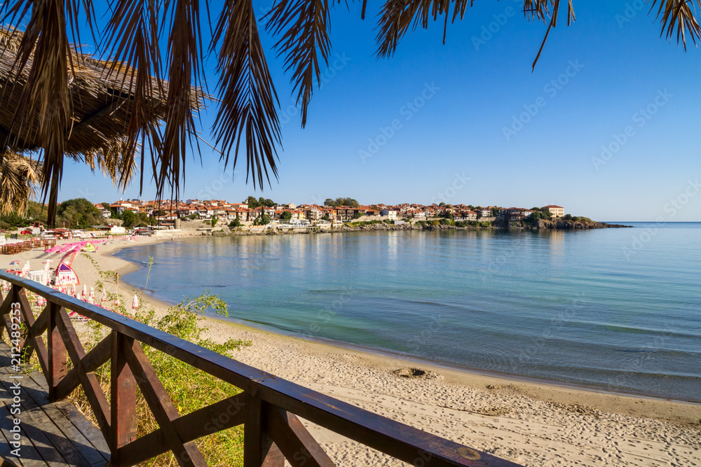 Seaside landscape - view from the cafe to the sandy beach with umbrellas and sun loungers in the town of Sozopol on the Black Sea coast in Bulgaria - obrazy, fototapety, plakaty 
