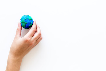 Wall Mural - Earth. Hand hold plastiline symbol of planet Earth globe on white background top view copy space