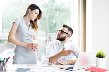 Wall Mural - Portrait of two modern entrepreneurs discussing startup project while working at desk in sunlit office