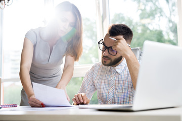 Wall Mural - Portrait of two modern entrepreneurs, man and woman, discussing startup project while working at desk in sunlit office