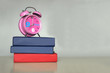 © Liliia - Background with alarm clock on stack of books over gray wall. Back to school concept with copy space