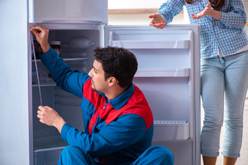 Man repairing fridge with customer