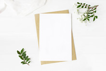 Feminine Wedding Stationery, Desktop Mock-up Scene. Blank Greeting Card, Craft Envelope, Baby's Breath Flowers, Silk Ribbon And Lentisk Branches. Old White Wooden Table Background. Flat Lay, Top View.