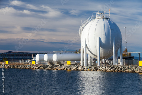 Cuadros en Lienzo Spherical gas holder stands on sea coast