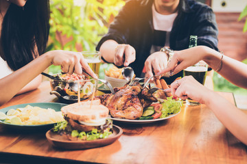 Asian friends enjoying eating turkey at restaurant.