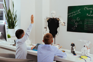 Wall Mural - smart pupil. nice smart boy holding his hand up while knowing the answer to the question