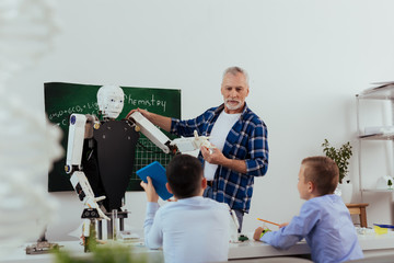 Wall Mural - technology of future. positive aged man looking at his pupils while telling them about robots