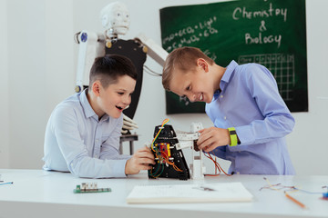 Wall Mural - modern classroom. nice cheerful boys looking at the robot while playing in the classroom