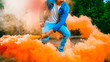 a young man in a blue jumpsuit t is holding a smoke bomb in his hands. A man is holding colored orange smoke