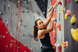 © alfa27 - Sporty young woman looking at camera while training in a colorful climbing gym. Free climber girl climbing up indoor