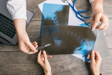 surgeon consultation with X-rays. Doctors and patients hands on the table. Top view from above. Professional medical care