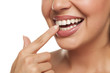 young woman touchng her teeth with her finger on white background
