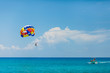 People flying on a colorful parachute towed by a motor boat