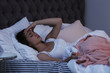 © New Africa - Young woman suffering from headache while lying in bed at night. Sleeping problems