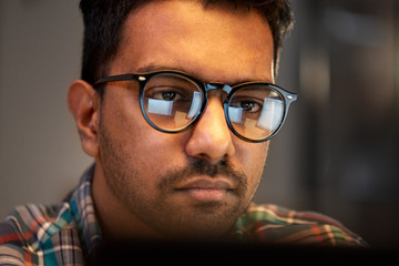 education, deadline and people concept - close up of creative man in glasses working at night office and thinking