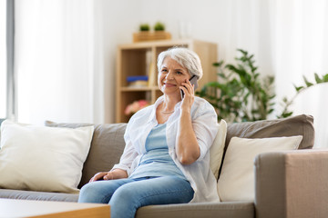 Poster - technology, communication and people concept - happy senior woman calling on smartphone at home